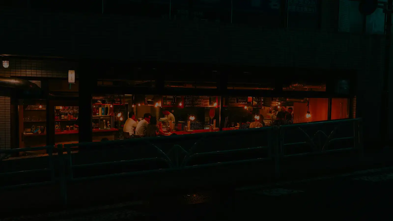 Interior iluminado de un restaurante visto desde la calle de noche