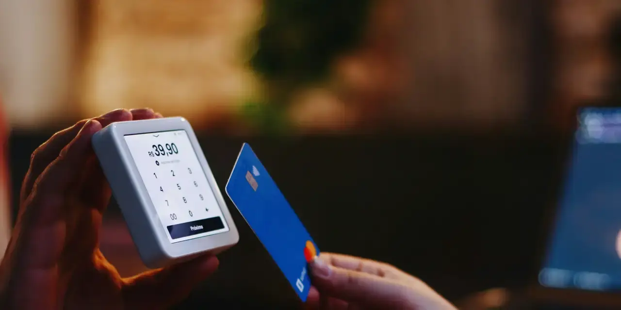Cliente acercando una tarjeta azul a un pequeño terminal de pago portátil