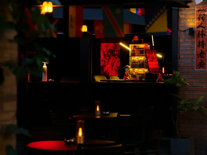 Terraza de un local de noche con mesas iluminadas en rojo